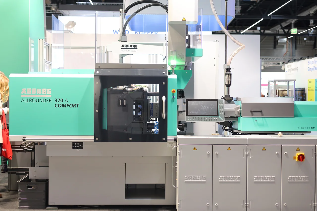 Injection-molding cell at an industry exhibition — third-party photographic reference