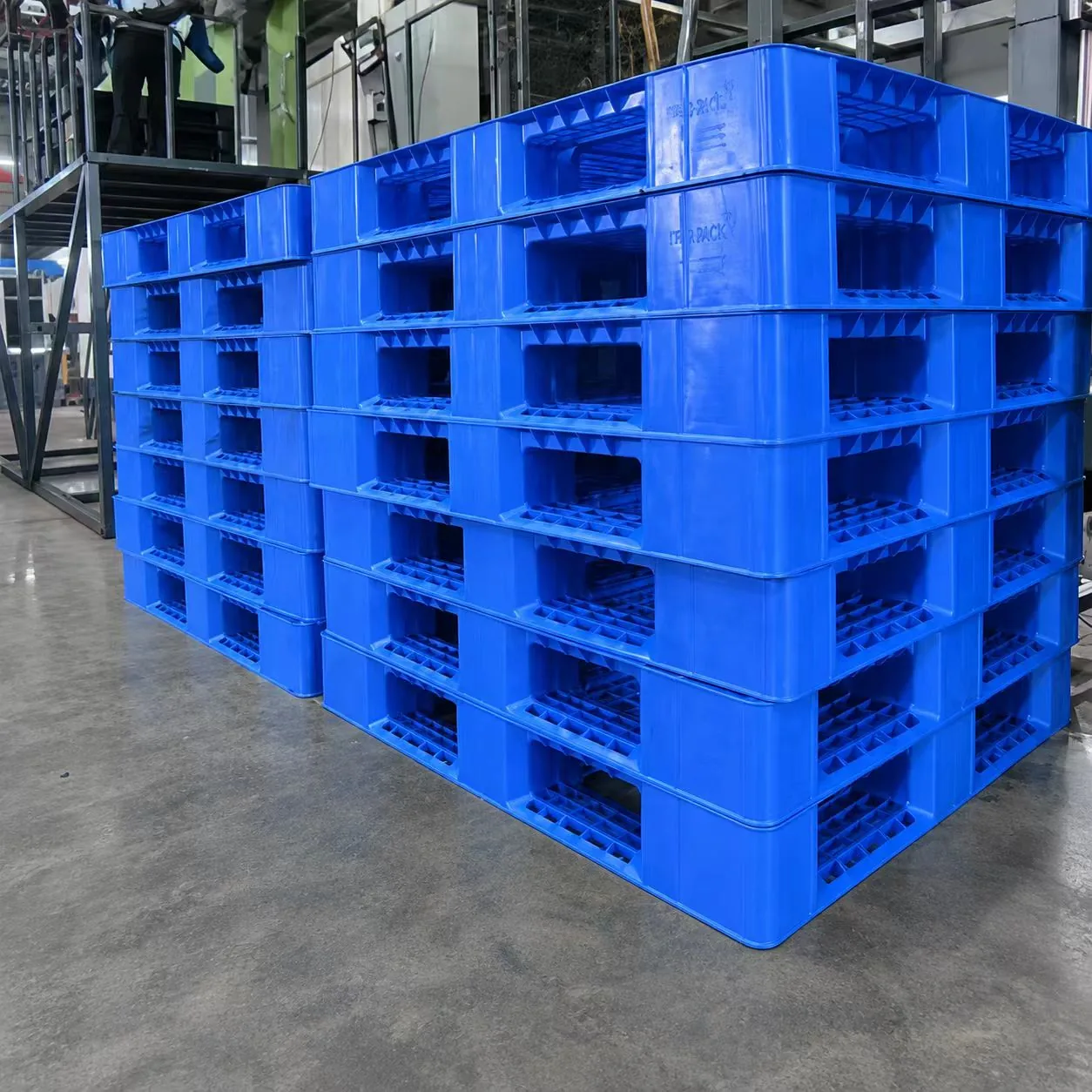 Stacks of blue molded plastic pallets in a workshop