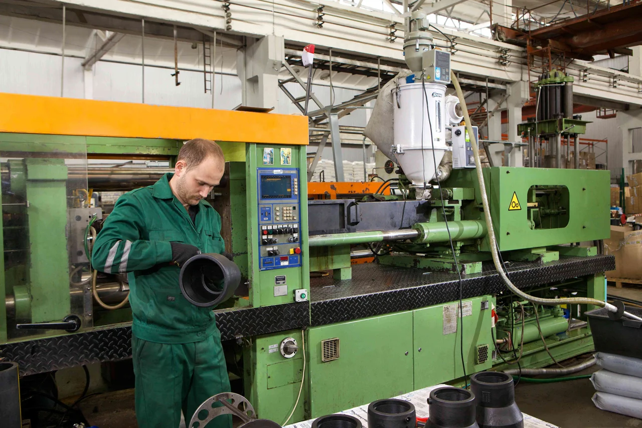 Operator at an injection-molding machine — third-party photographic reference